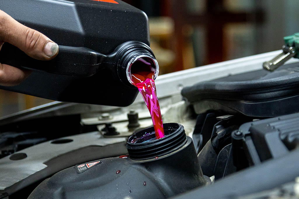 The pink radiator water is filling in the radiator